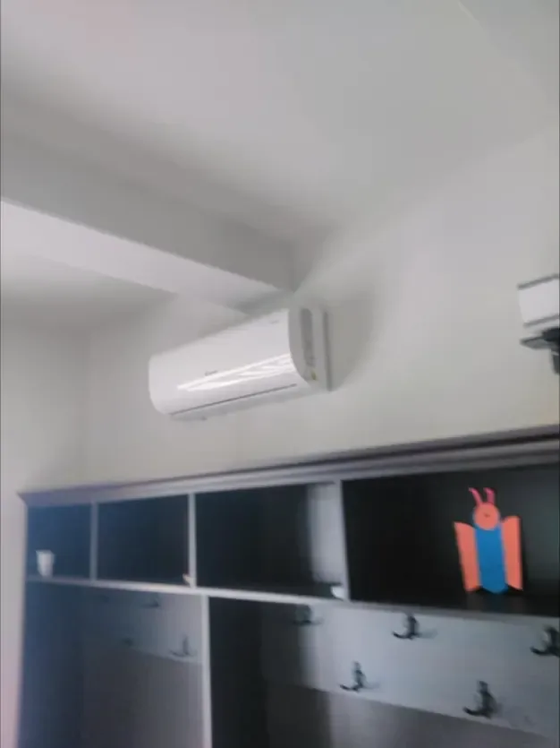 Aer condiționat montat aproape de tavan, într-o cameră mobilată