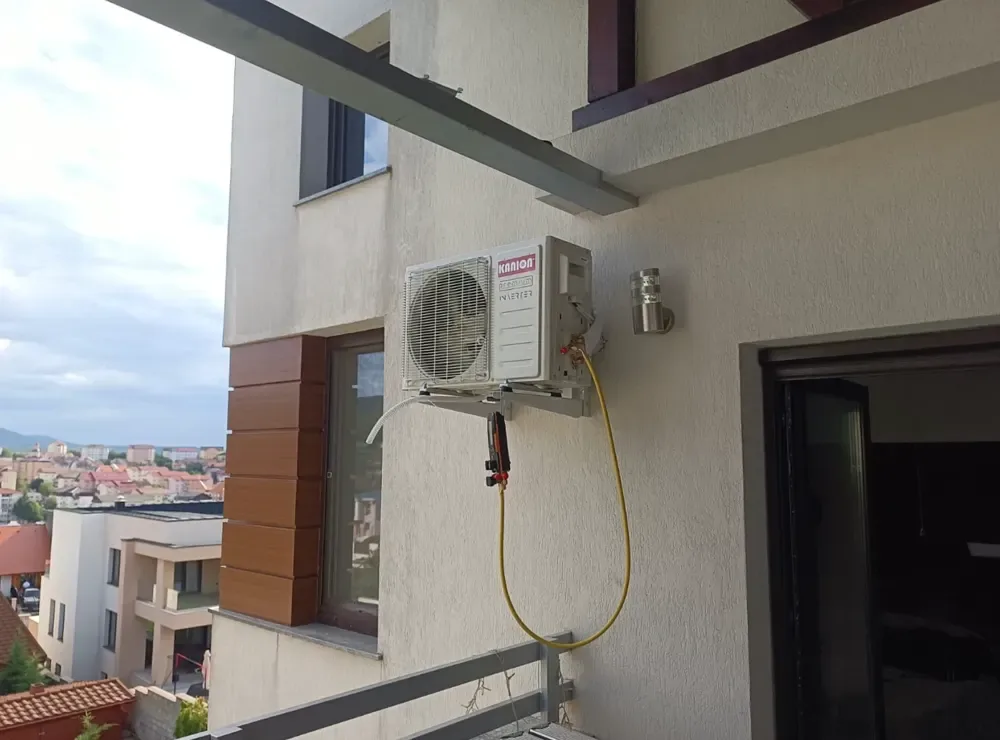 Unitate exterioară de aer condiționat pe un balcon, cu vedere spre oraș